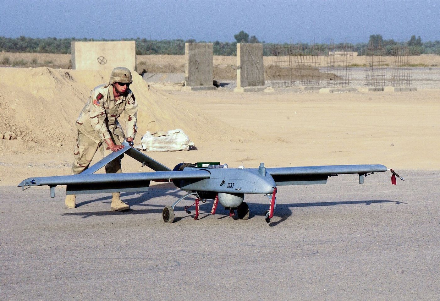 An operator handling a fixed-wing unmanned aircraft on a launcher before flight.