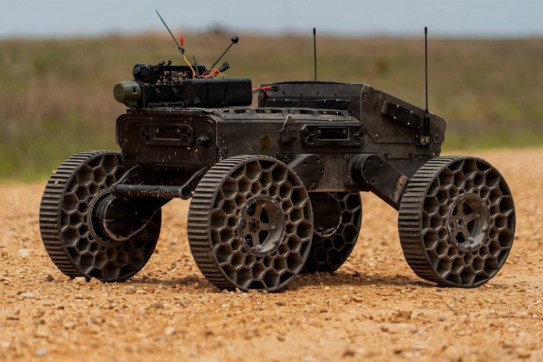 A six-wheeled unmanned ground vehicle on loose gravel, away from any prepared surface.